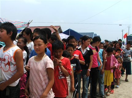  孩子们的脸庞被烈日晒得红红的，数日的劳顿奔波或许让他们不能像在校园中那般整洁，脚上此时仅有的拖鞋保护着稚嫩的小脚丫，但孩子们仍保持着整齐有序的队伍