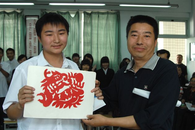 学生将现场制作的剪纸作品送给自己的父亲