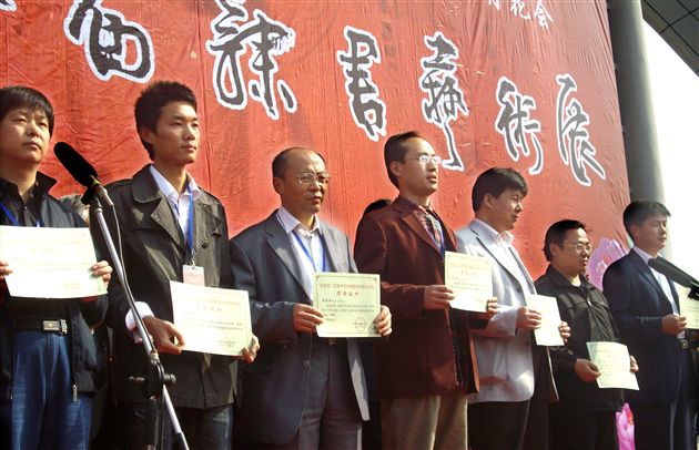 郭彦飞老师(左三)在第二届隶书艺术展暨隶书创作论坛领奖台上</p><p>　　